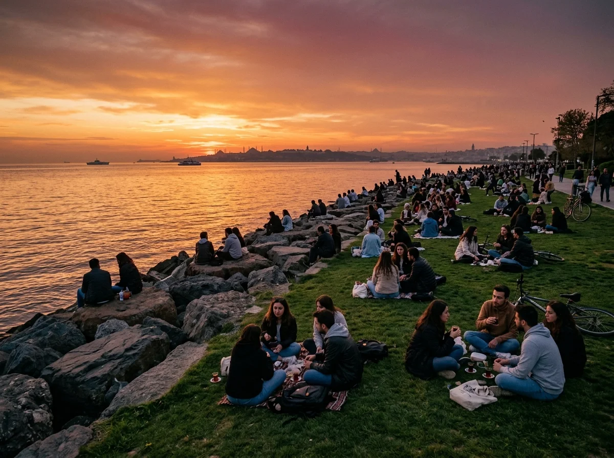 People relaxing on the grassy seaside park and rocks at Moda waterfront in Kadıköy watching the sunset over the Marmara Sea